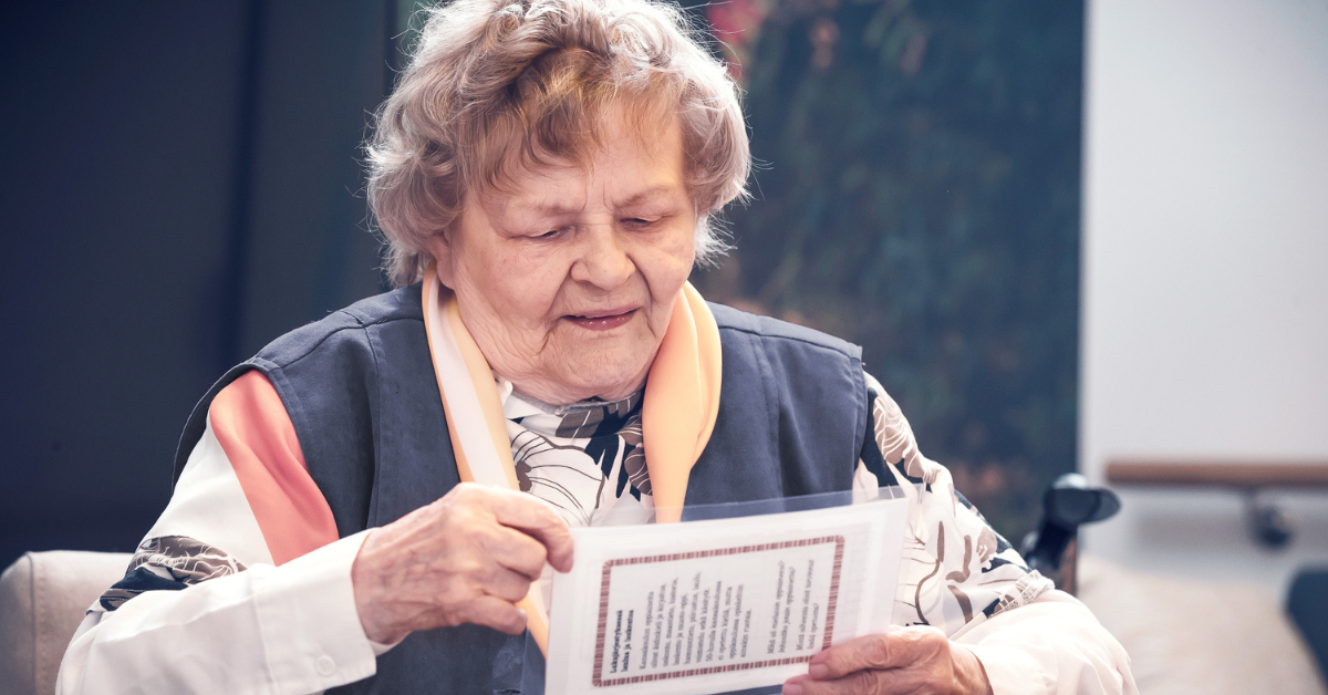 Vanhempi nainen lukemassa käsissään olevaa paperia sisätiloissa.