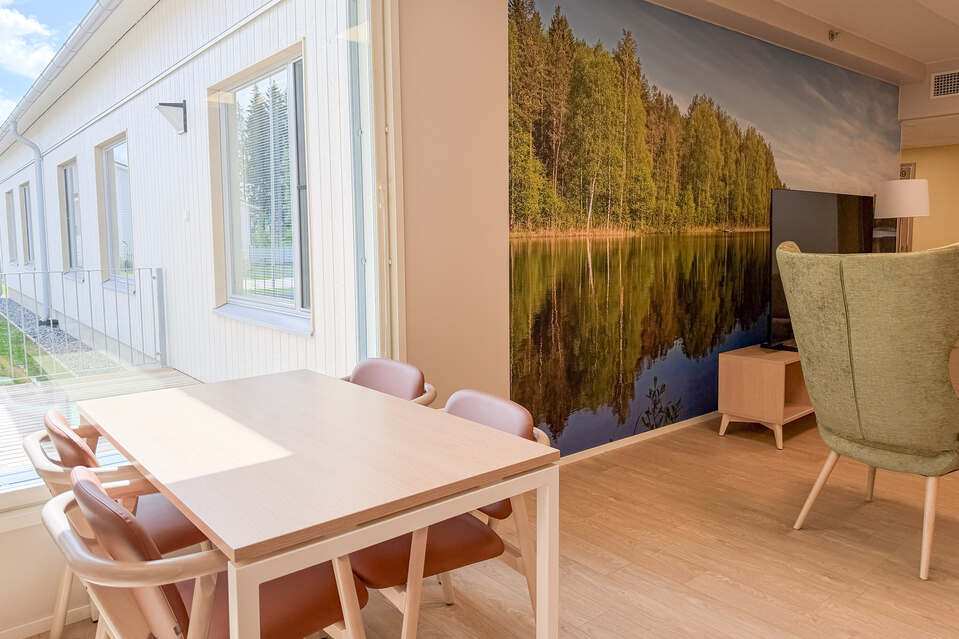 Kanteleen yleinen tila, ruokapöytä ikkunan vieressä ja maisematapetti