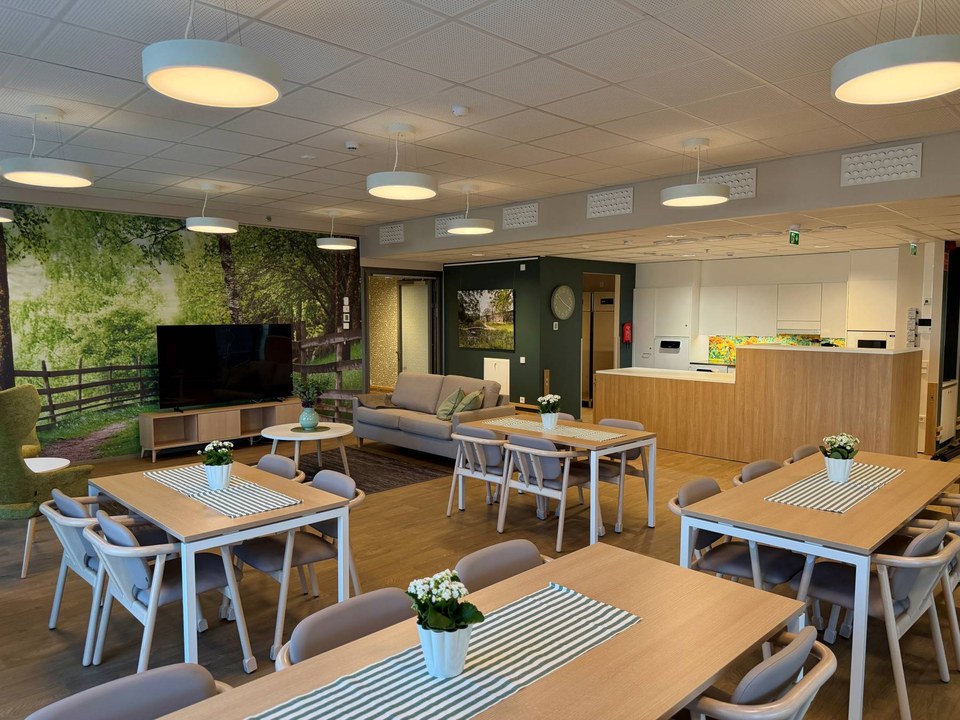 Attendo Kuisman ruokailutila, neljän hengen pöytiä sekä valokuvaseinä