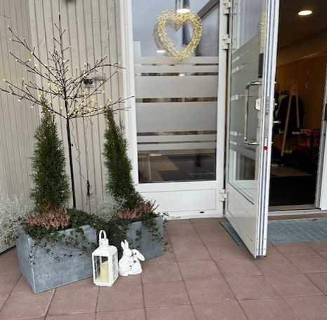 Sisääntulo Lammenrantaan, ovi auki, ovensuu koristeltu joulukoristeilla