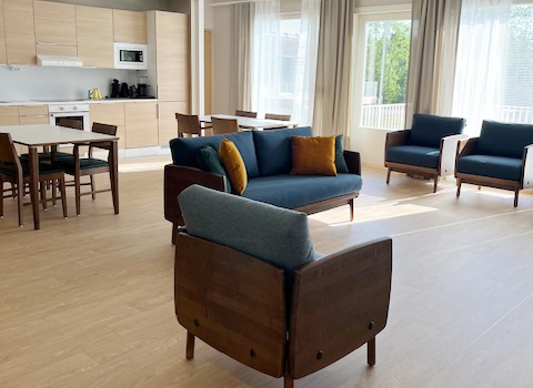 Lammenrannan yhteistila, nojatuoleja ja sohva, taustalla ruokapöytä ja isot ikkunat