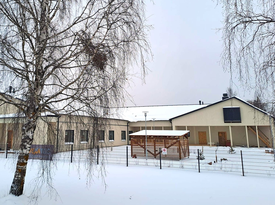 Vaalea yksikerroksinen rakennus talvisella säällä, lunta maassa