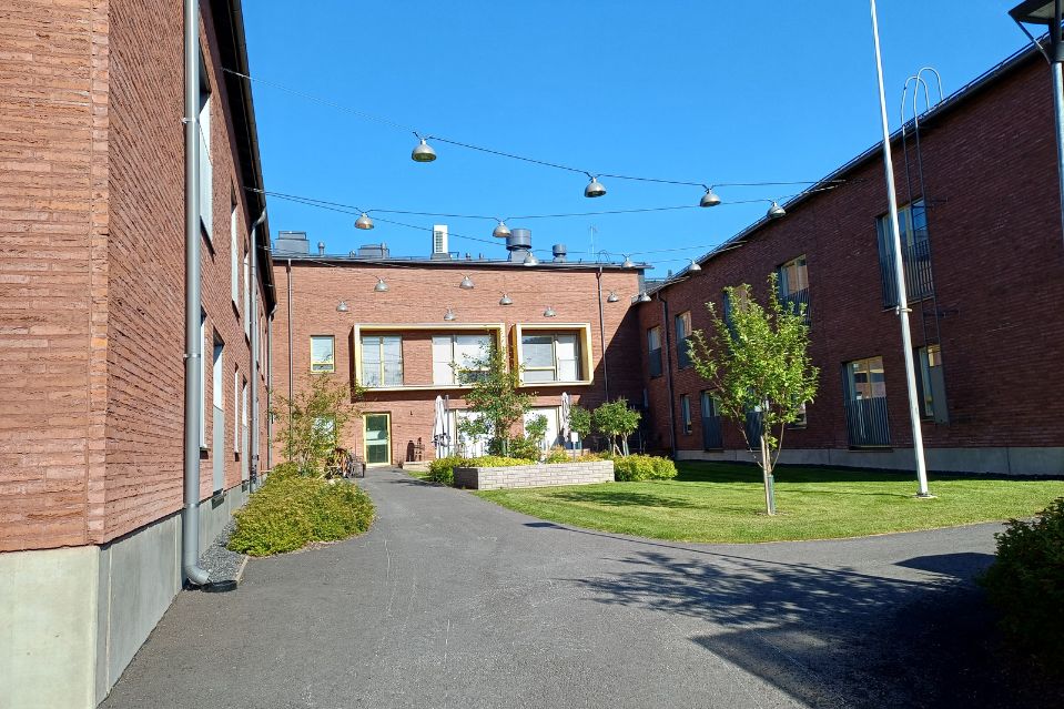 Pitäjänpirtti kesäisenä päivänä, etualalla vihreää nurmikkoa