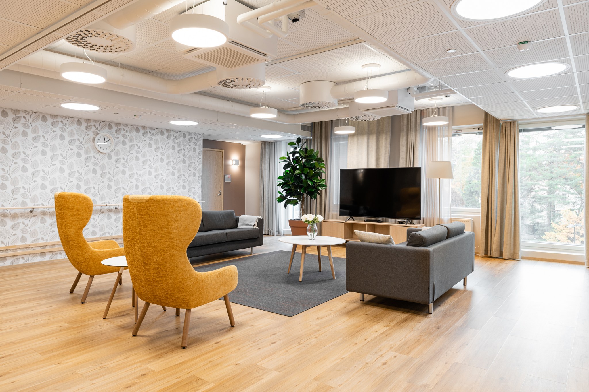 Attendo-kodin olohuone, jossa on kaksi nojatuolia, kaksi sohvaa, sohvapöytä, viherkasvi sekä televisio