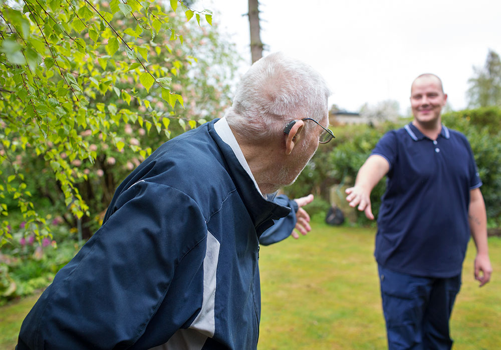 Ikäihminen ulkoilemassa hoitajan kanssa kesäsäällä