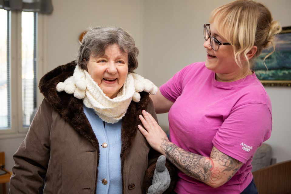 Hoitaja pukee nauravaista hoivakodin asukasta ulkoilua varten