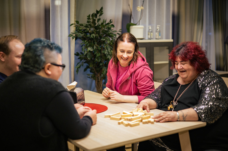 Asukkaat pelaavat lautapeliä pöydän ääressä