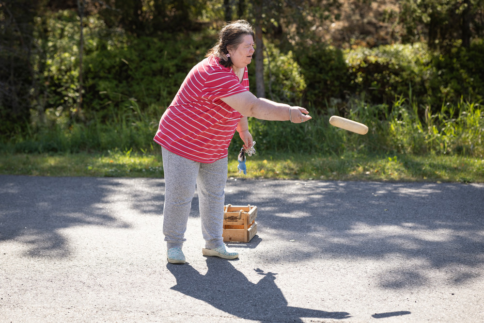 Kehitysvammainen henkilö heittää mölkkyä pihalla kesäisessä auringonpaisteessa