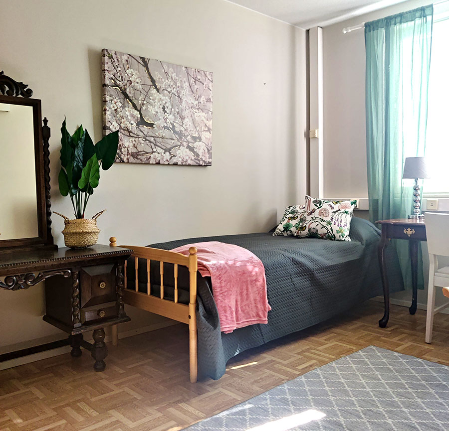 Hoitaja auttaa asukasta pukemaan takkia