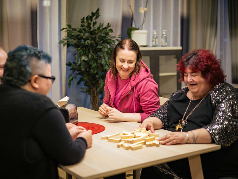 Palvelukodin asukkaat pelaamassa lautapeliä pöydän ääressä