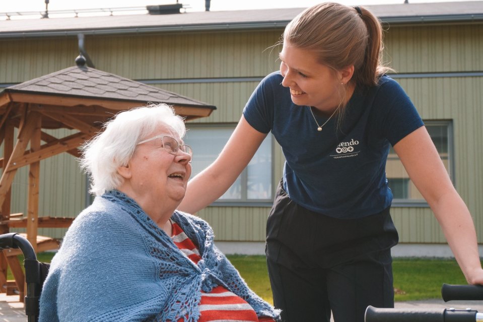 Kuvassa ik&auml;ihminen ja fysioterapeutti yhdess&auml; ulkona