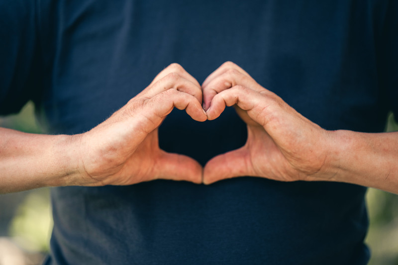 Kädet muodostavat sydänmerkin tummansinistä taustaa vasten