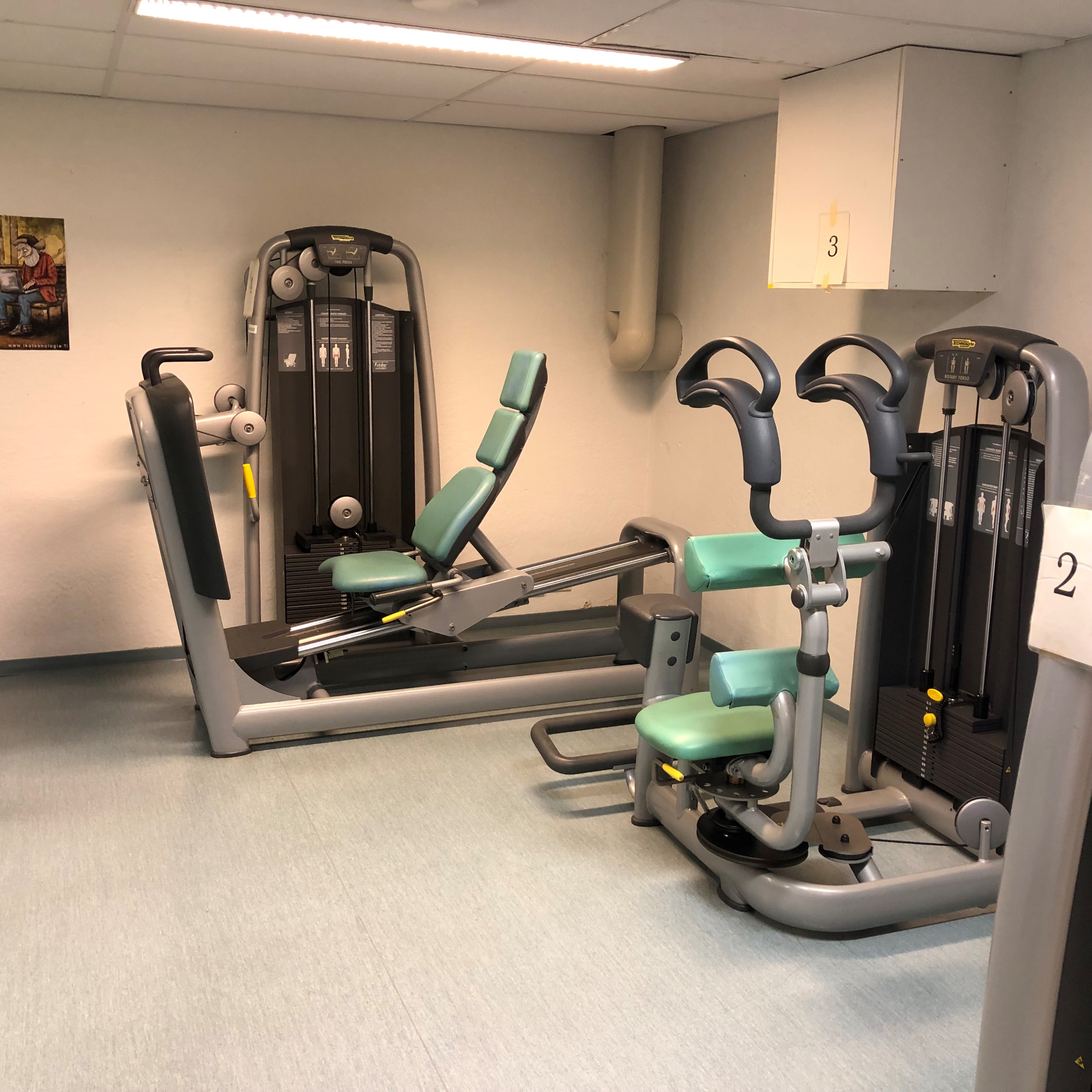 Kuntosalin laitteita sisätiloissa, mukaan lukien jalkaprässi ja ylävartalon harjoituslaite
