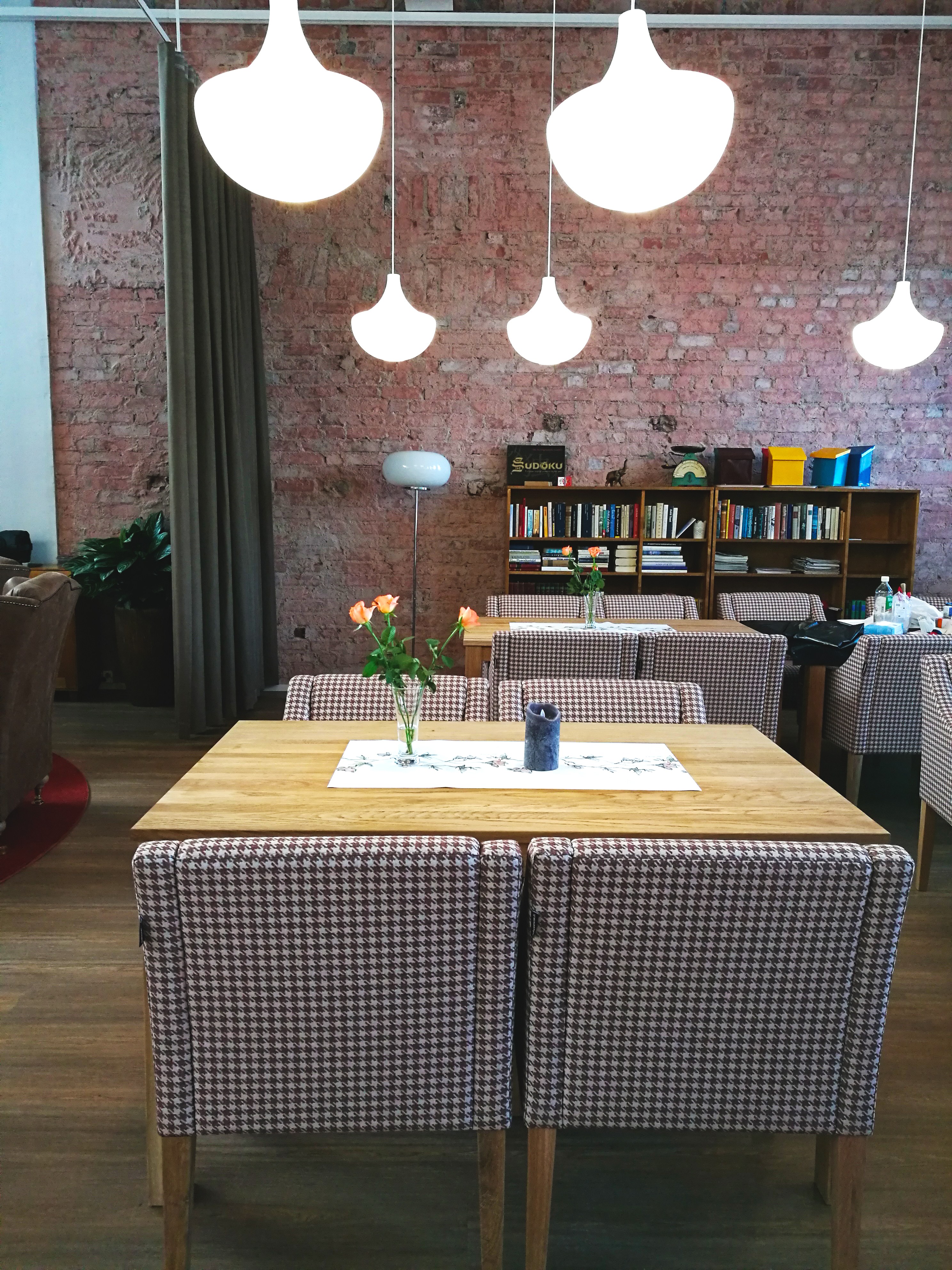Attendo Taivallahden olohuonessa pöytä, jossa on neljä tuolia, valaisimia sekä punatiilinen seinä taustalla.