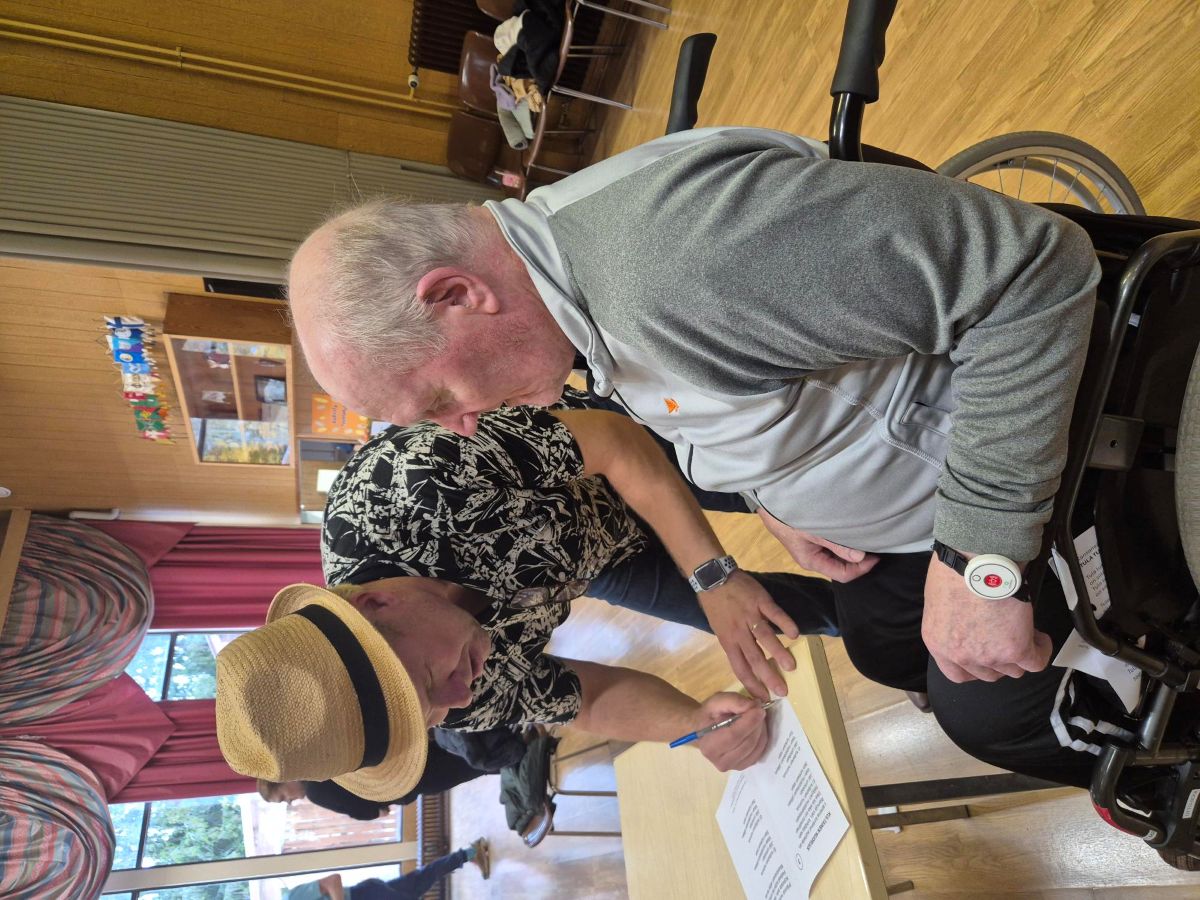 Hoivakodin asukas saa nimikirjoituksen esiintyjältä iltamissa