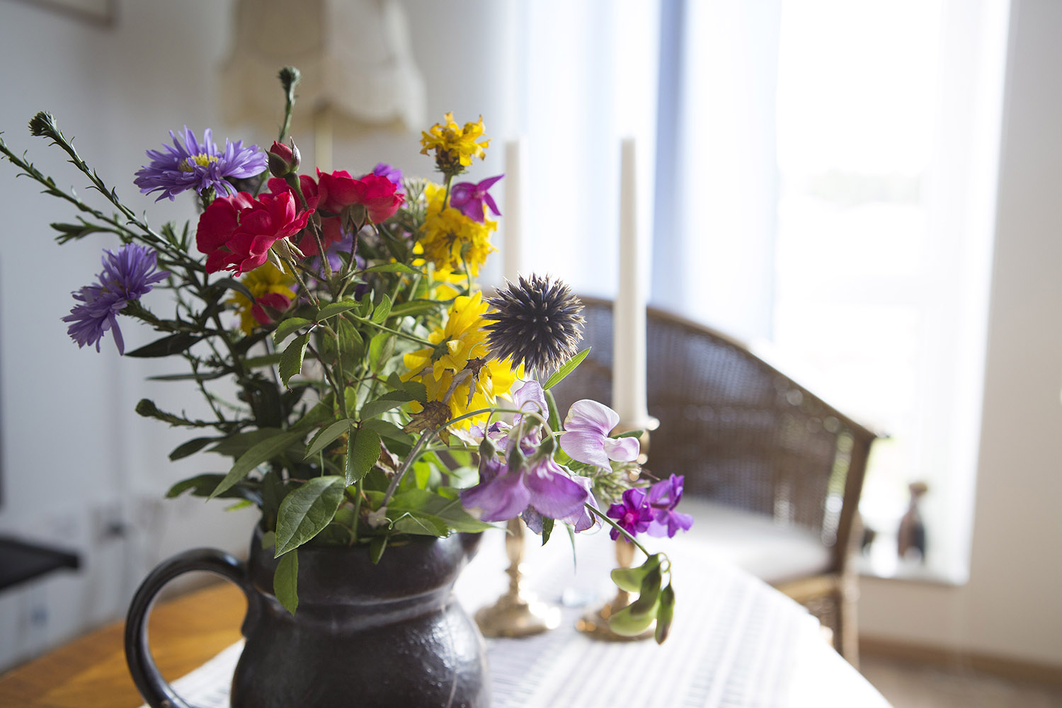 Värikkäitä kukkia maljakossa pöydällä, jossa on valkoinen pöytäliina